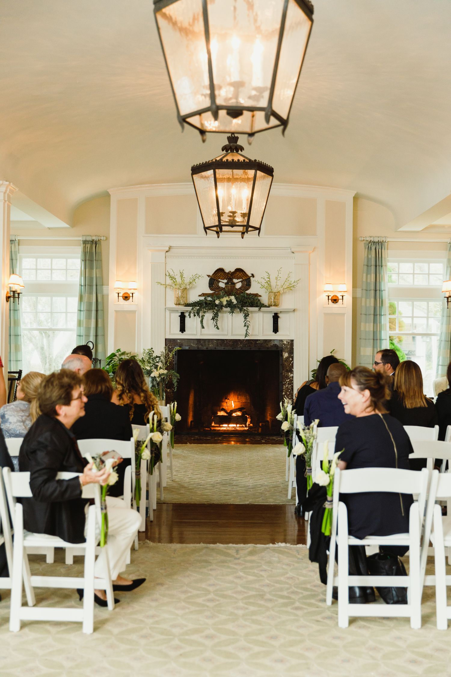 Elegant wedding venue with white chairs and hanging lanterns in a bright reception hall.