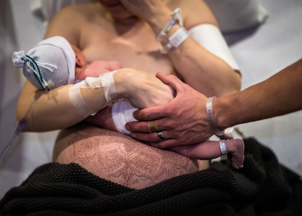 Healthcare providers assist with skin-to-skin contact between parent and newborn in hospital.