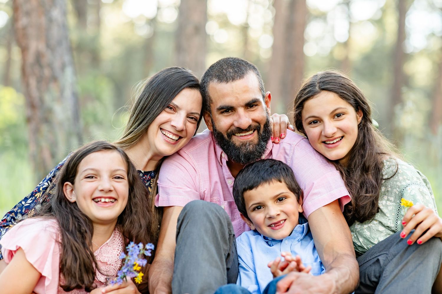 Parents and their three children snuggle and laugh in the wildflowers during their family session in Colorado Springs.