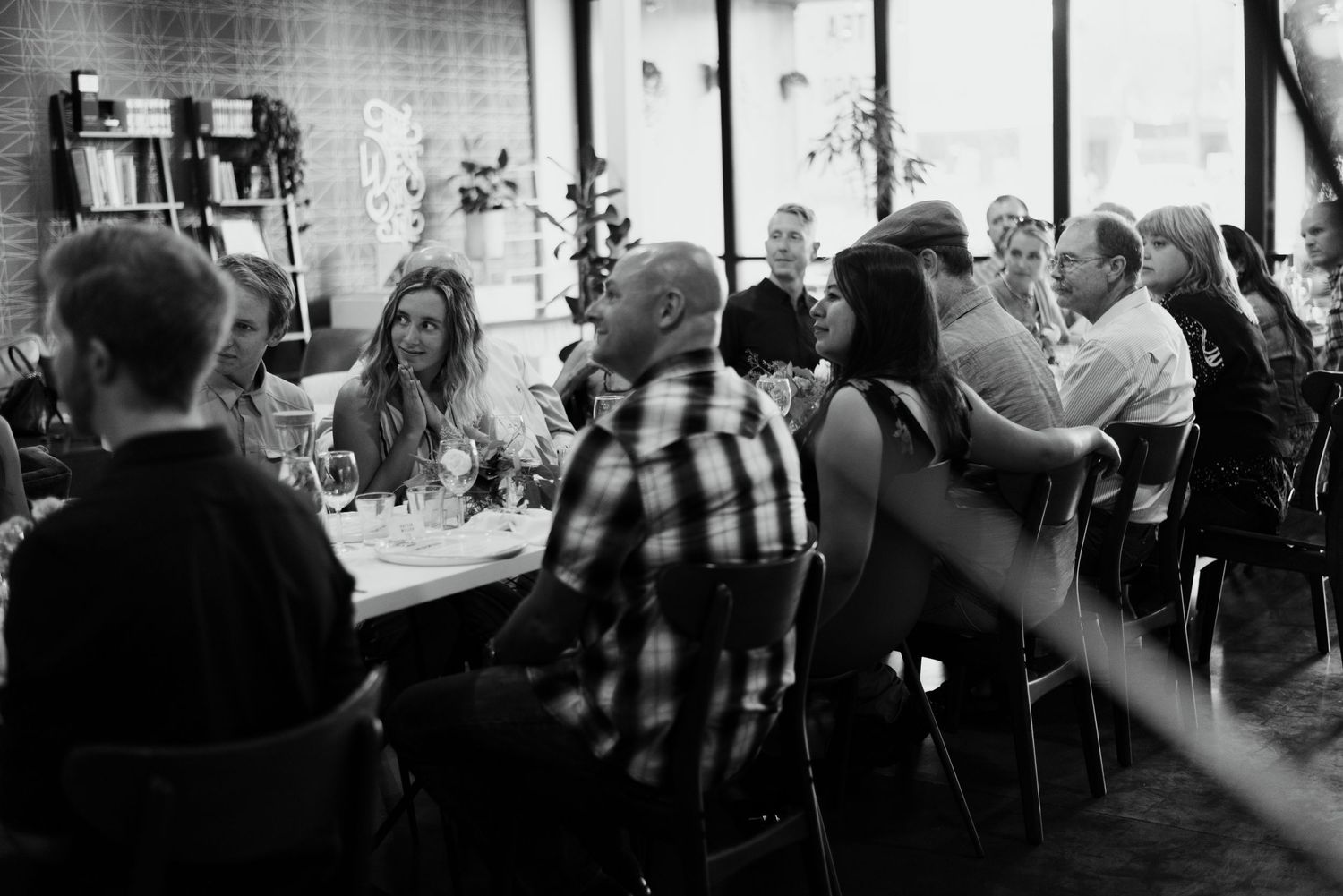 Black and white image of people gathering in a dimly lit restaurant or bar setting.