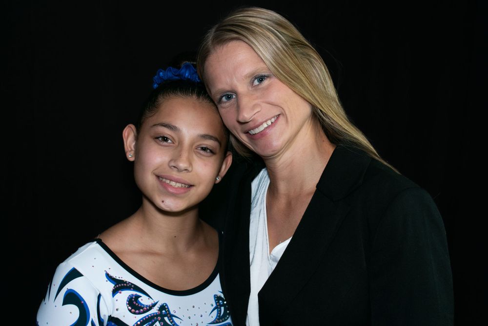 Two people smile warmly for a portrait against a black background.
