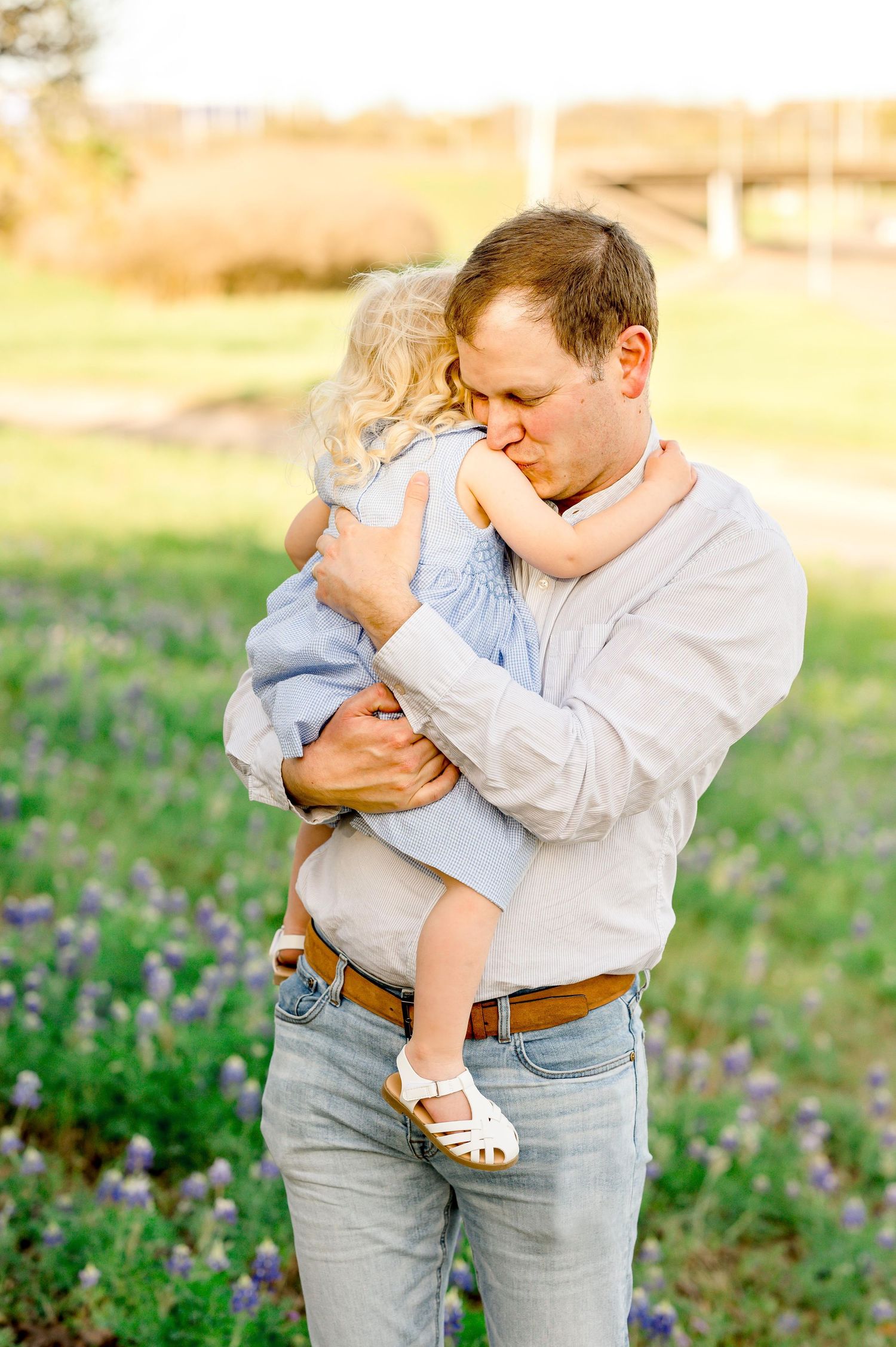 father kissing is daughter on the shoulder during a portrait session at sunset during family photography session houston