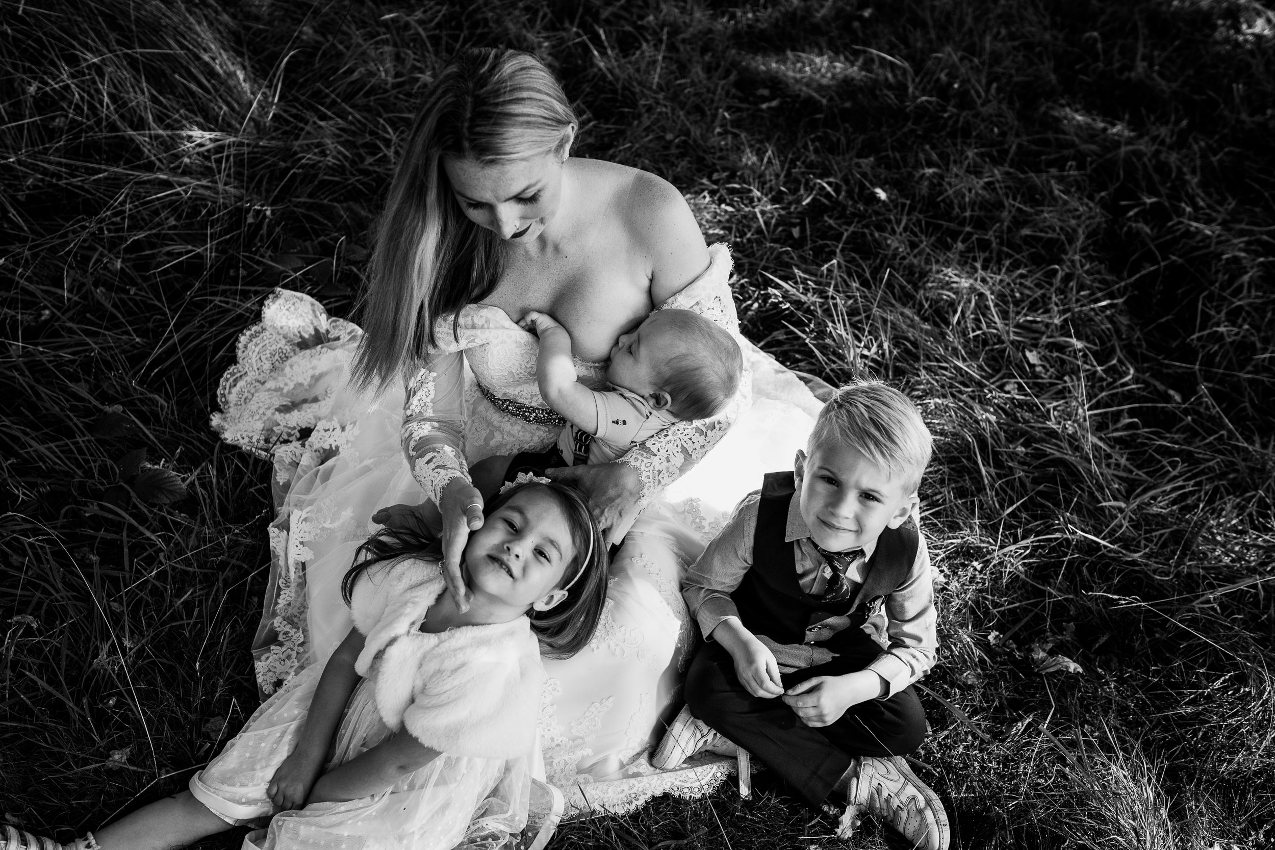 Bishops Stortford family photographer, Hertfordshire, mother breastfeeding with siblings cuddling her, natural family