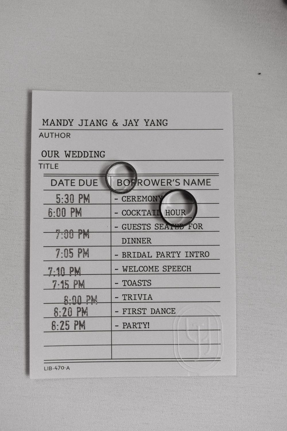 Wedding day timeline schedule with rings photographed in black and white.