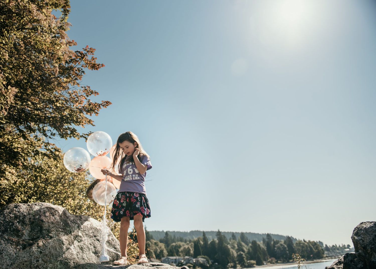 Candid moment captured with white balloons on a scenic rocky overlook.
