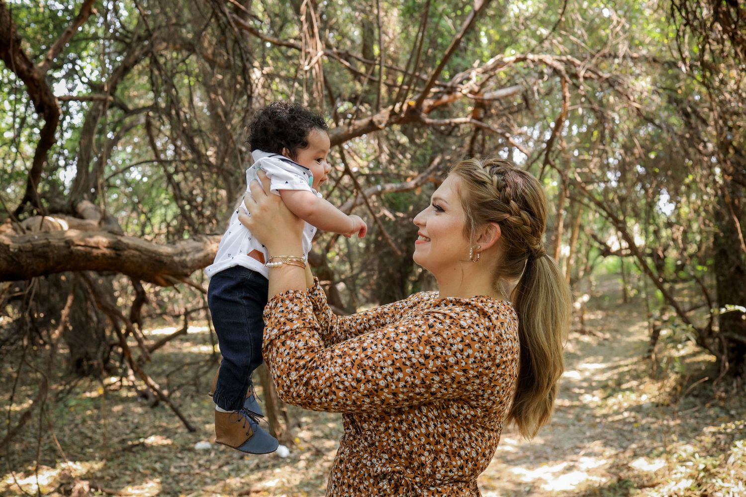 Mother lifting toddler during family session in Gauteng with natural, candid style in outdoor woodland setting