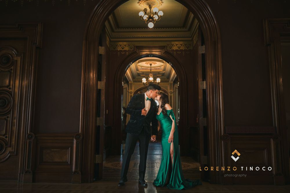 A romantic couple poses in an elegant archway with dramatic lighting.
