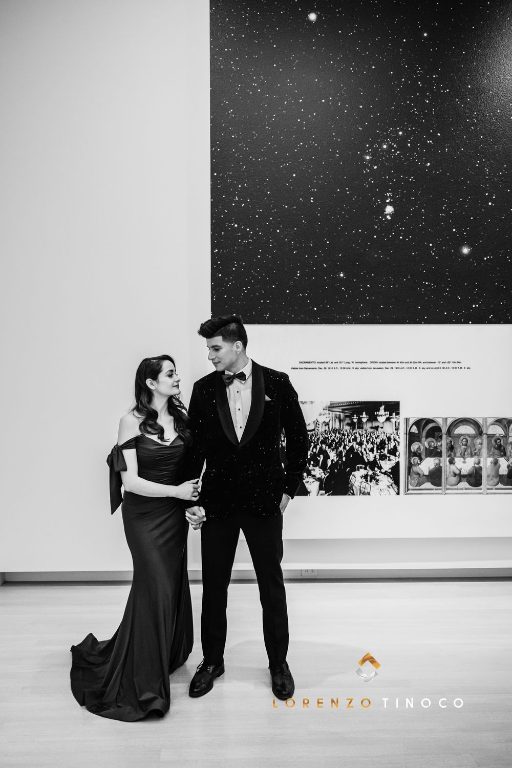 A black and white photo of a couple posing beneath a starry display in an art gallery.