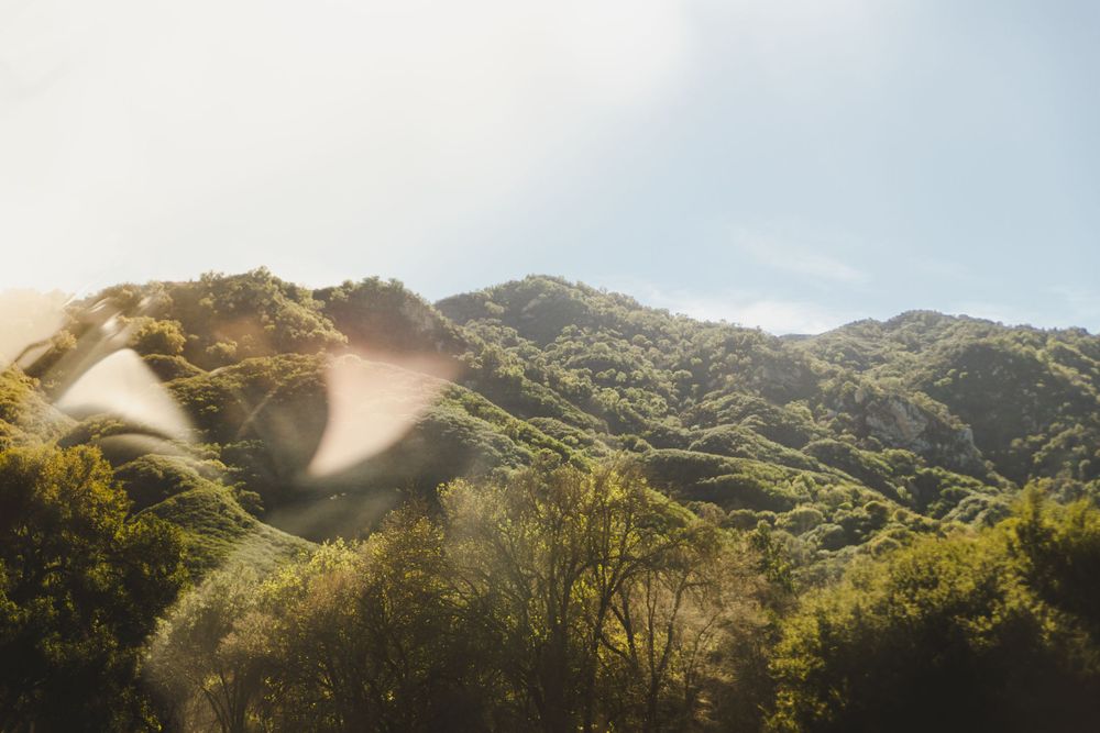 Scenic mountain landscape with sunlight streaming through green hills.