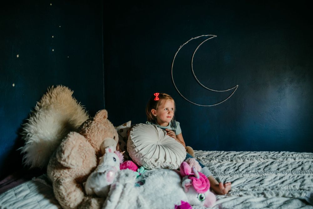portrait of child on bed looking towards windown in-home family photography portland oregon