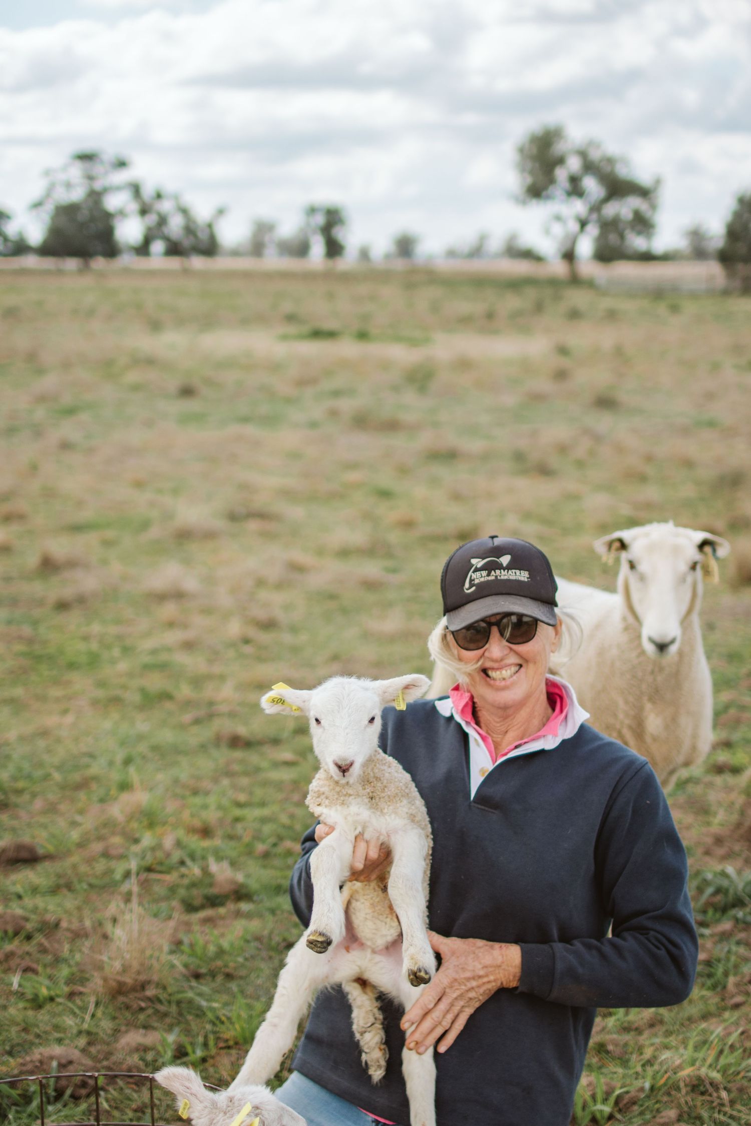 NEW ARMATREE BORDER LIECESTERS OWNER JENNY HOLDING A LAMB WITH THE EWE CLOSE BEHIND IN A GRAZING PADDOCK