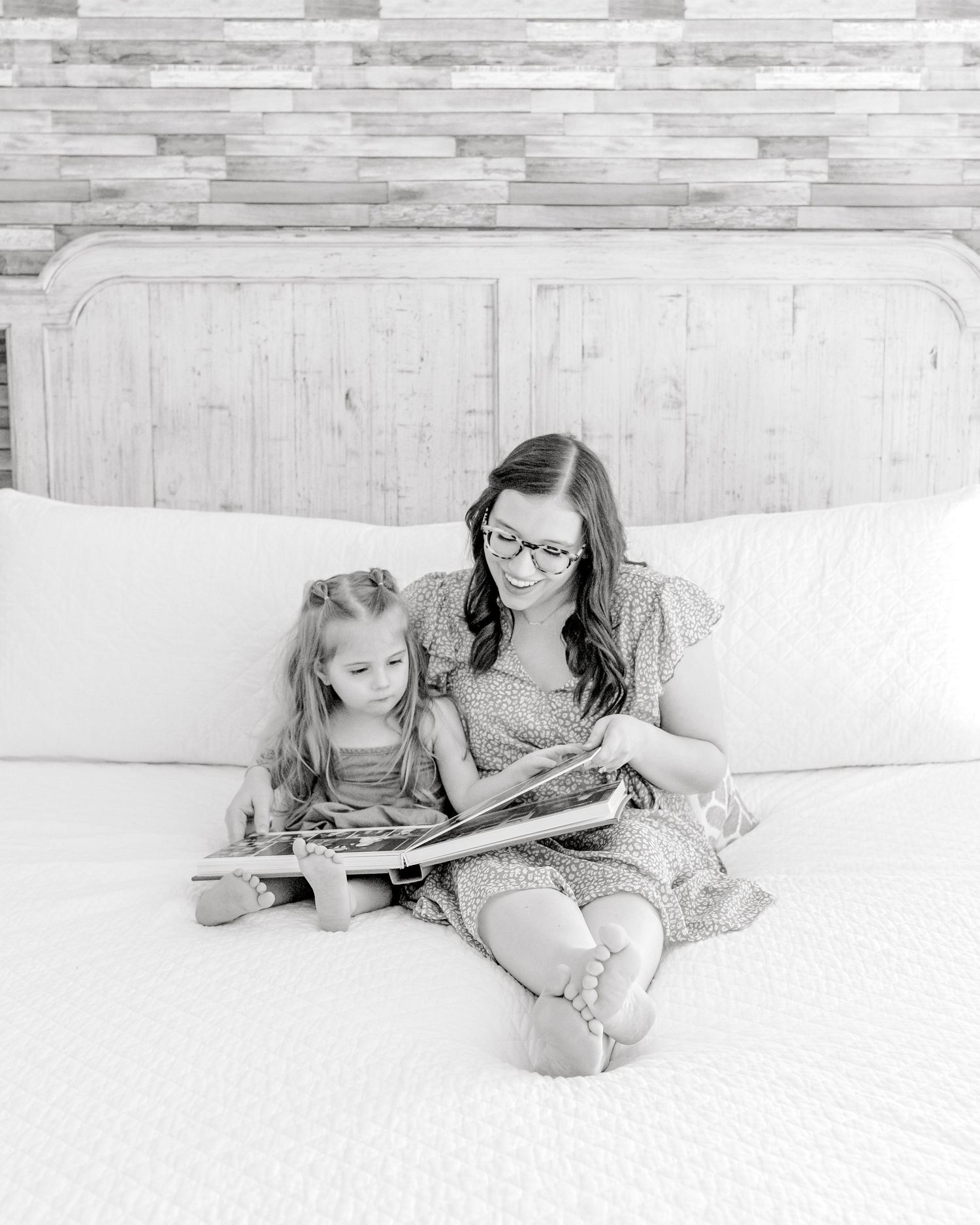 mom and daughter looking at photo album together on the bed