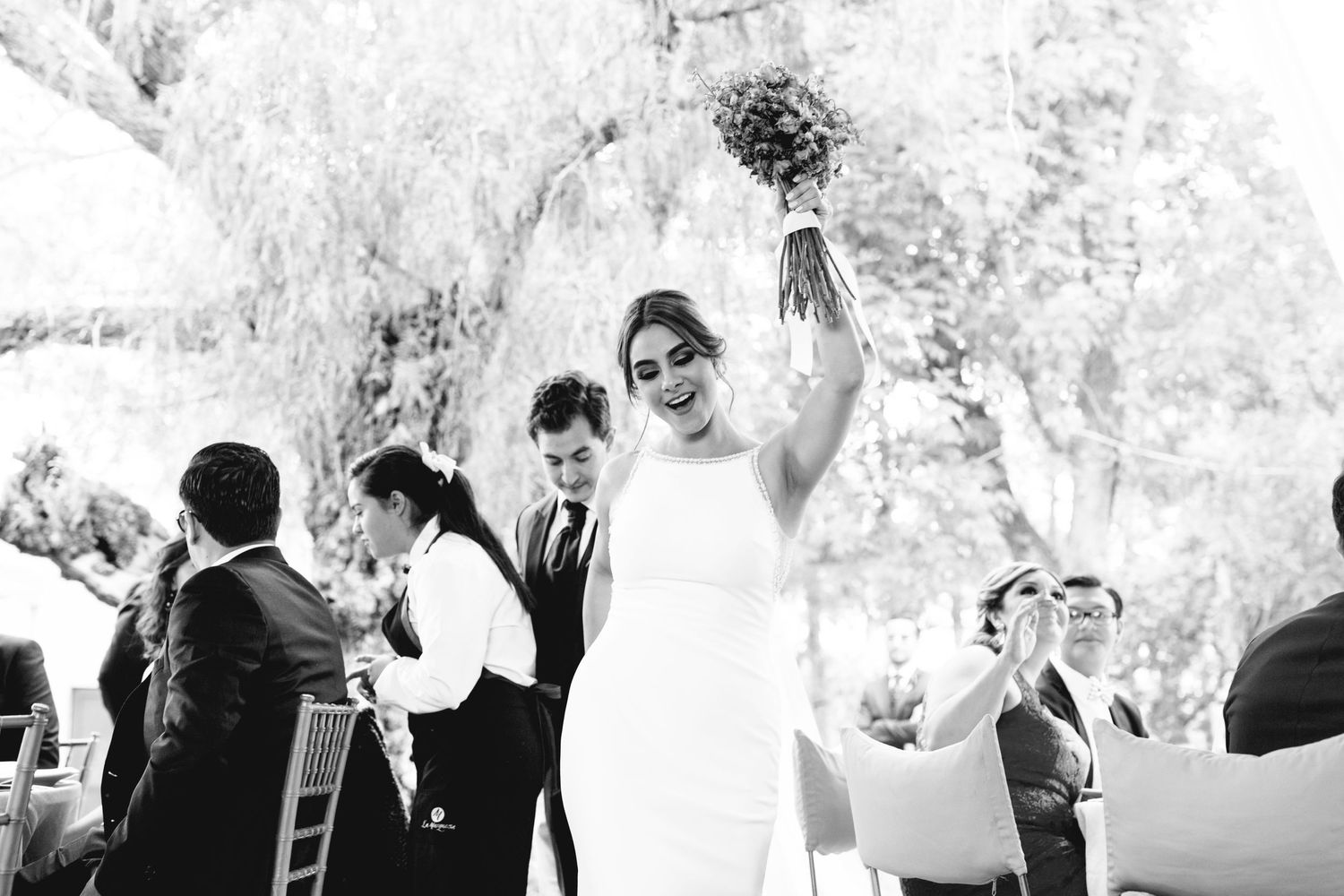 Black and white photo of celebratory moment at outdoor wedding reception.