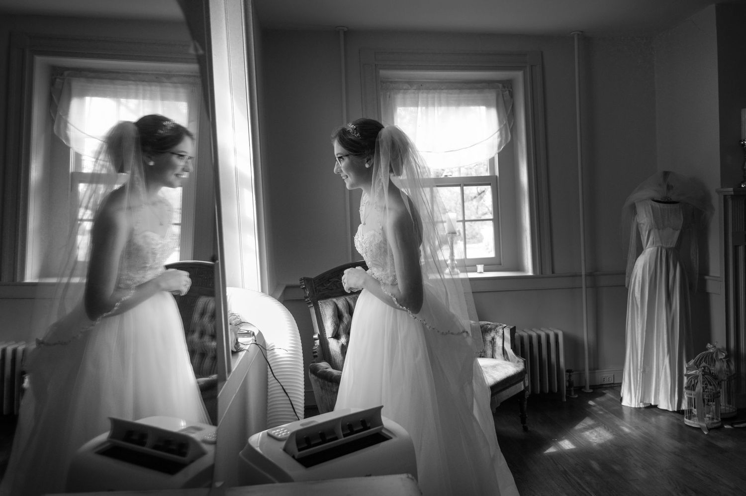 Bride in white wedding dress reflected in mirror during wedding day preparations.