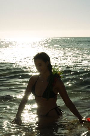 shimmering water glistening as a girl is walking out of the ocean during an early morning at the beach