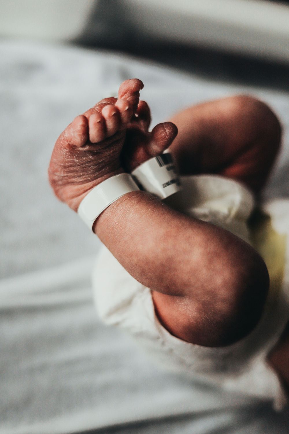 Close-up shot of tiny newborn baby feet with hospital ID tag attached and white cloth wrapping. terre haute family wedding photographer