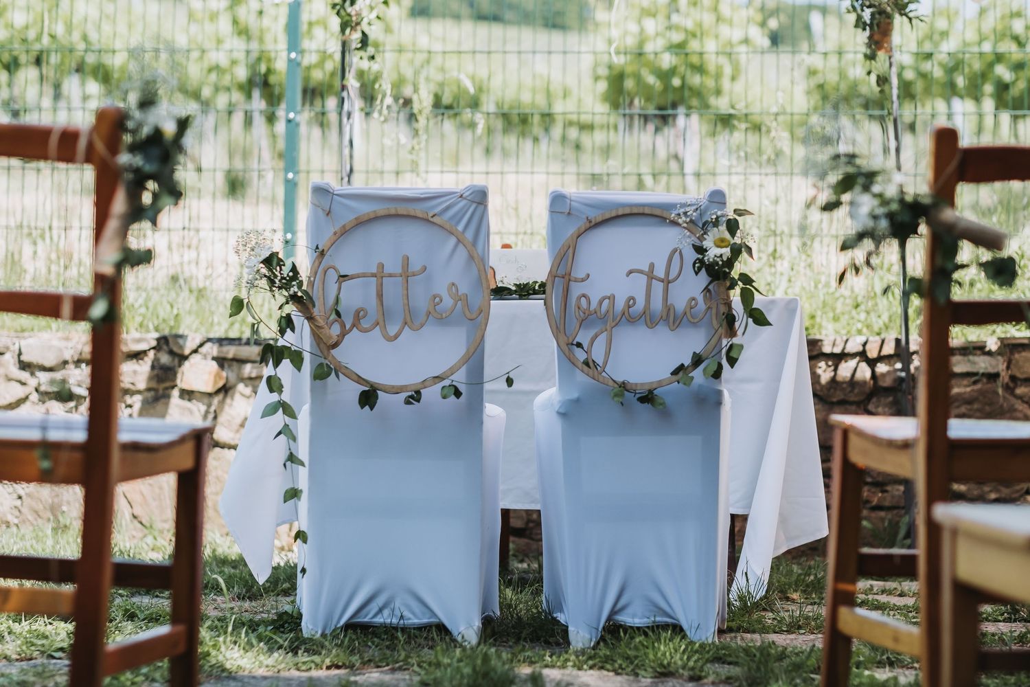 Garden wedding ceremony setup with white chairs and floral decorations.