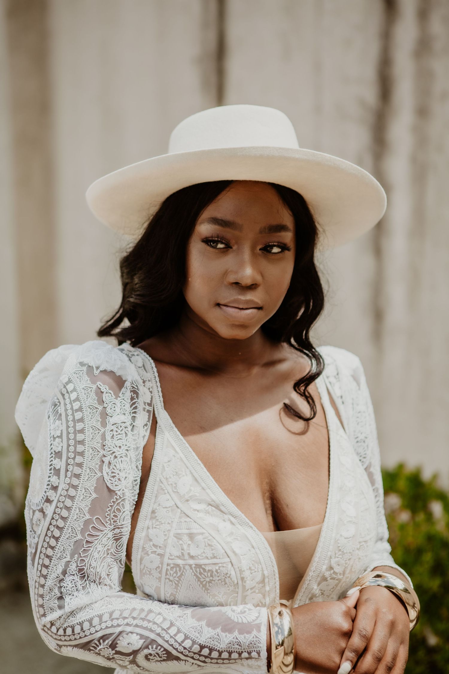 A person wearing a white lace dress and wide brim hat poses in multiple romantic portrait shots.