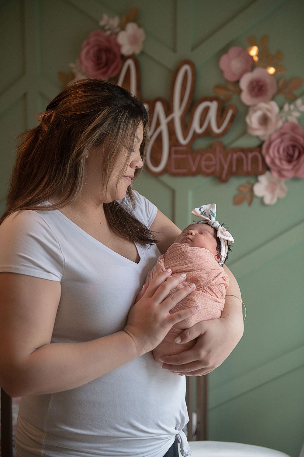 A nursery scene with pink floral wall decor and soft lighting creates a dreamy atmosphere.