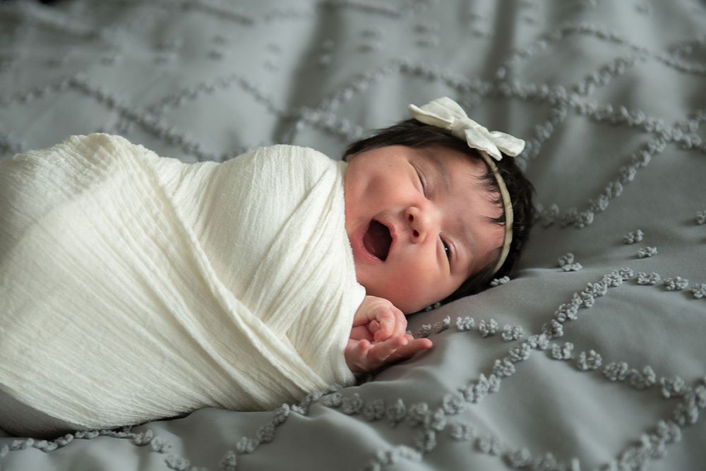 A sleeping infant peacefully rests on white textured bedding.