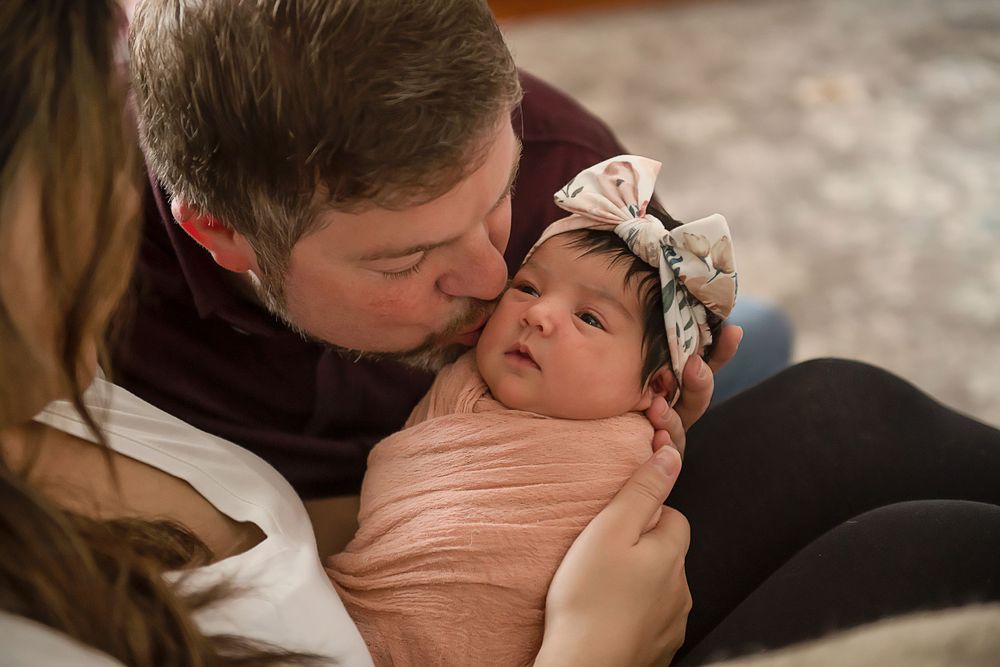 Intimate lifestyle photography of a family bonding with their newborn in warm lighting.