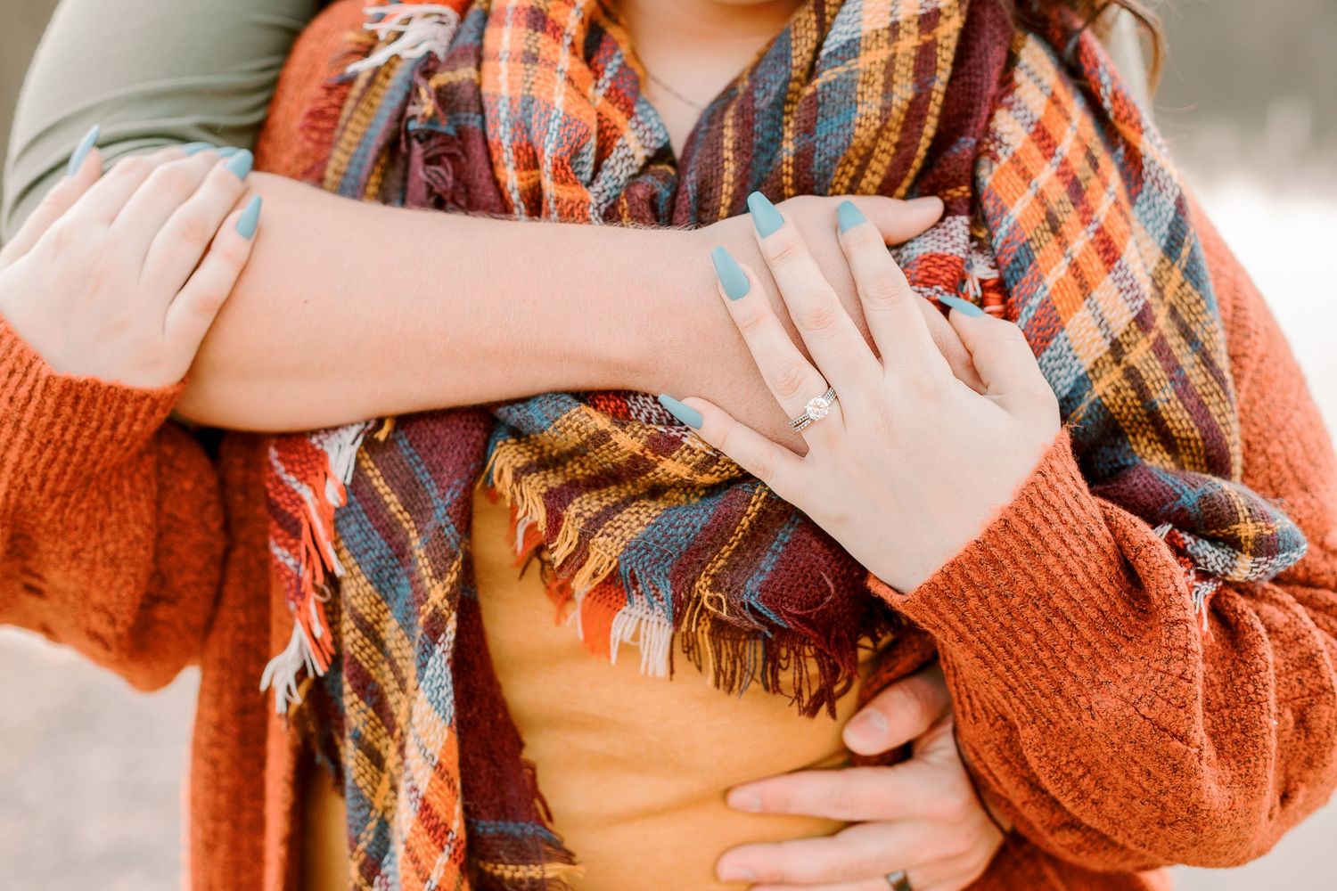 Person wearing orange plaid scarf and sweater in casual autumn portrait.