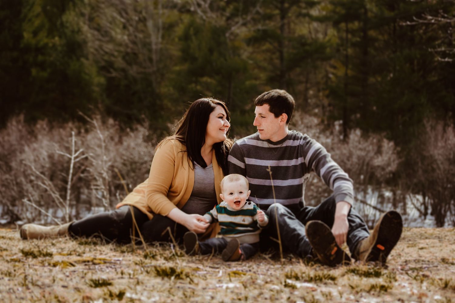 A family sitting together on grass during a casual outdoor photo session.