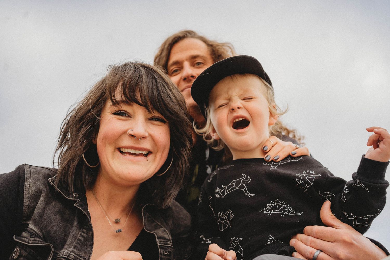 Joyful outdoor portrait against cloudy sky showing pure happiness and laughter.