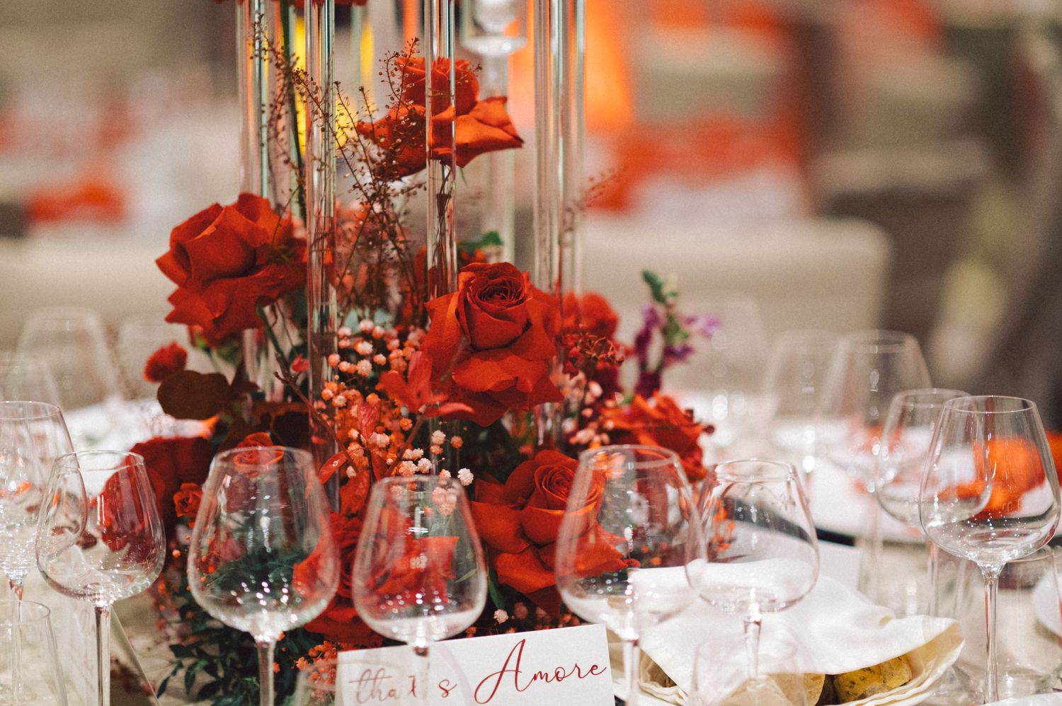 Romantic red rose centerpiece with crystal glassware on decorated dining table.