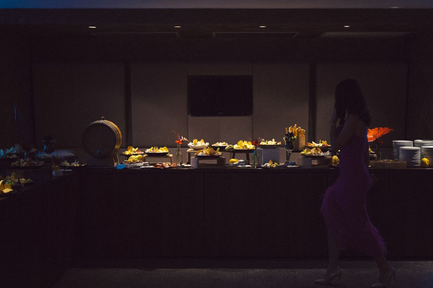 Dimly lit buffet table with glowing display of food and drinks.