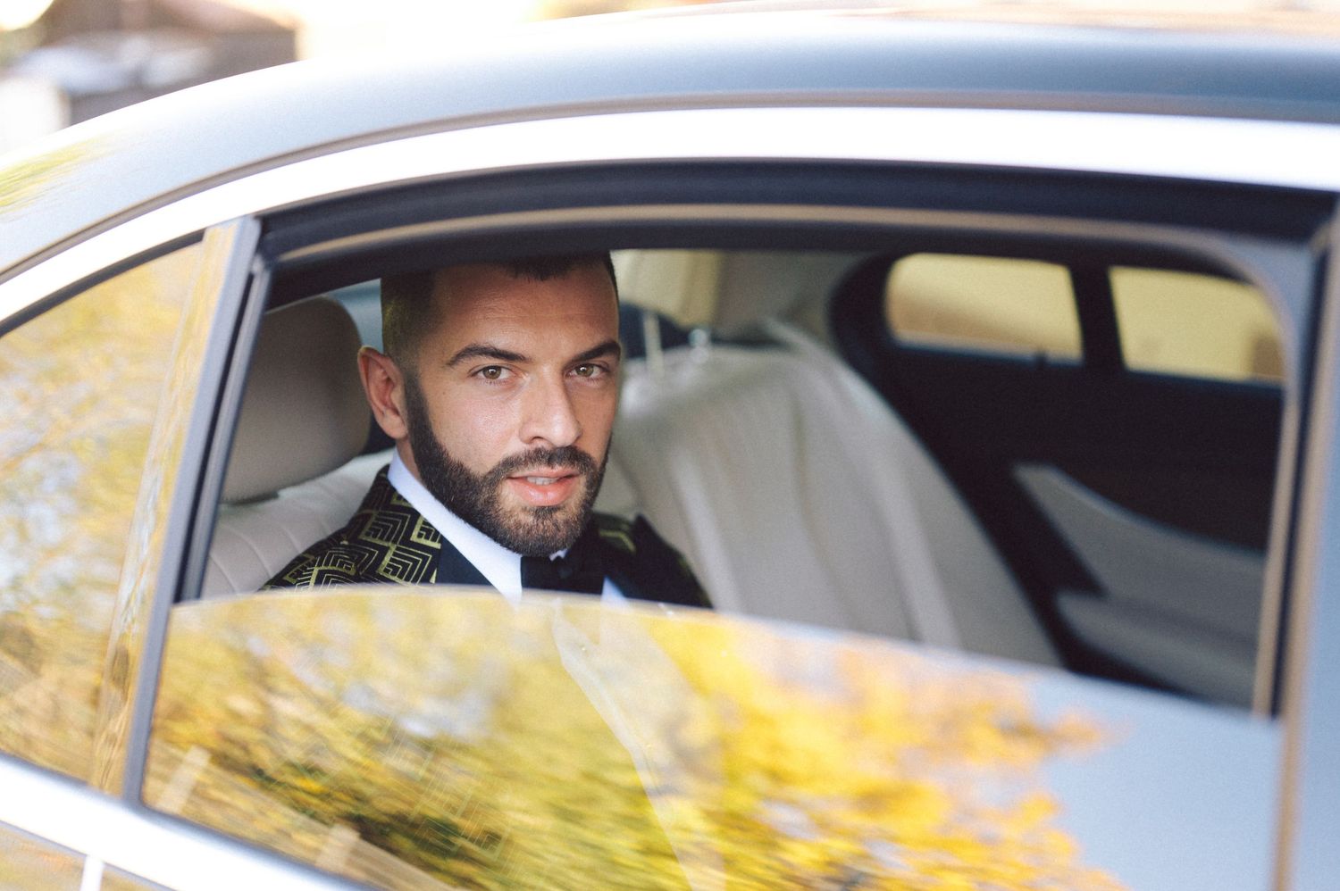 View through a car window showing a gold patterned tuxedo against white interior.