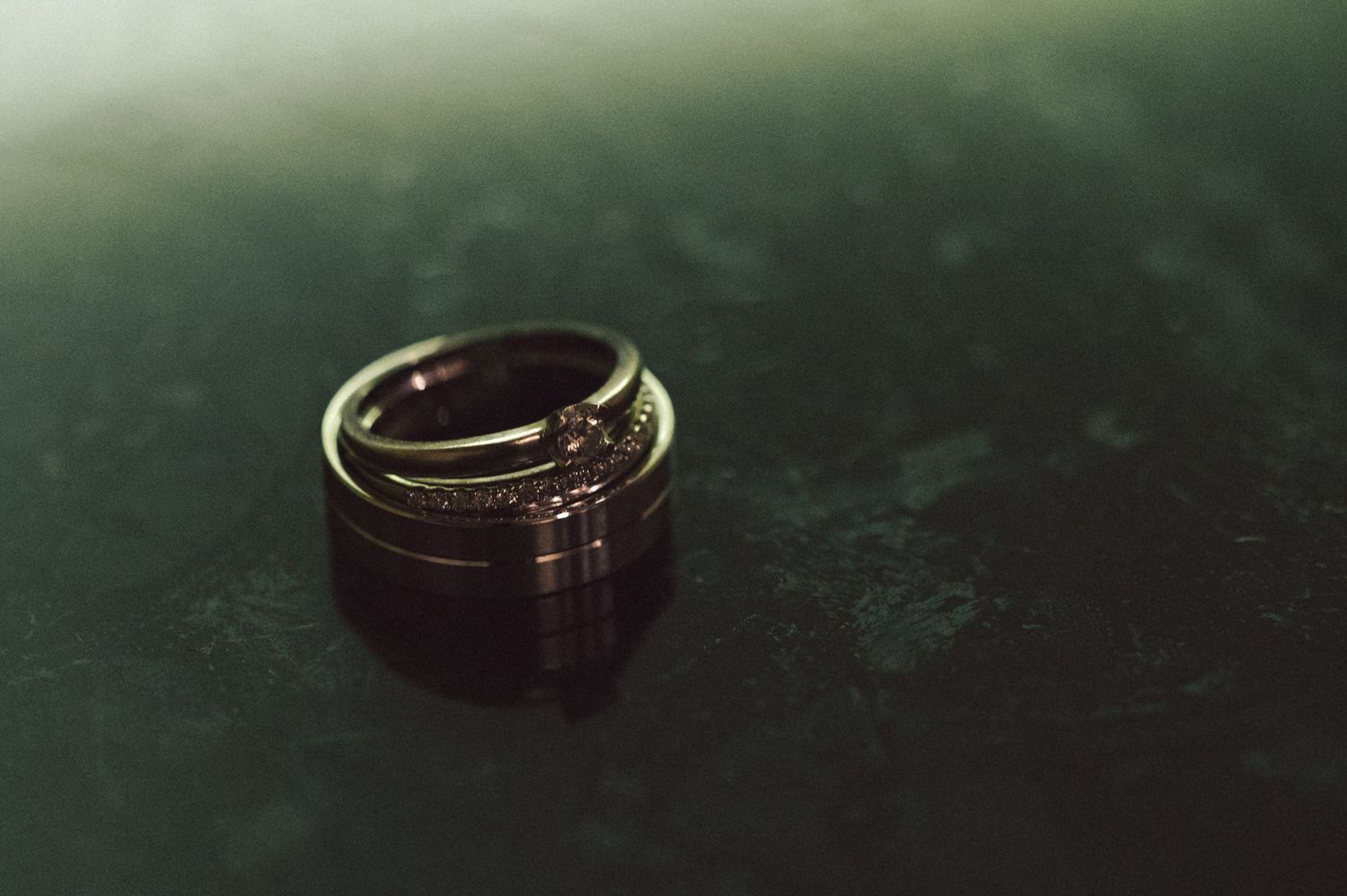 A wedding ring photographed in dramatic lighting on a dark surface.