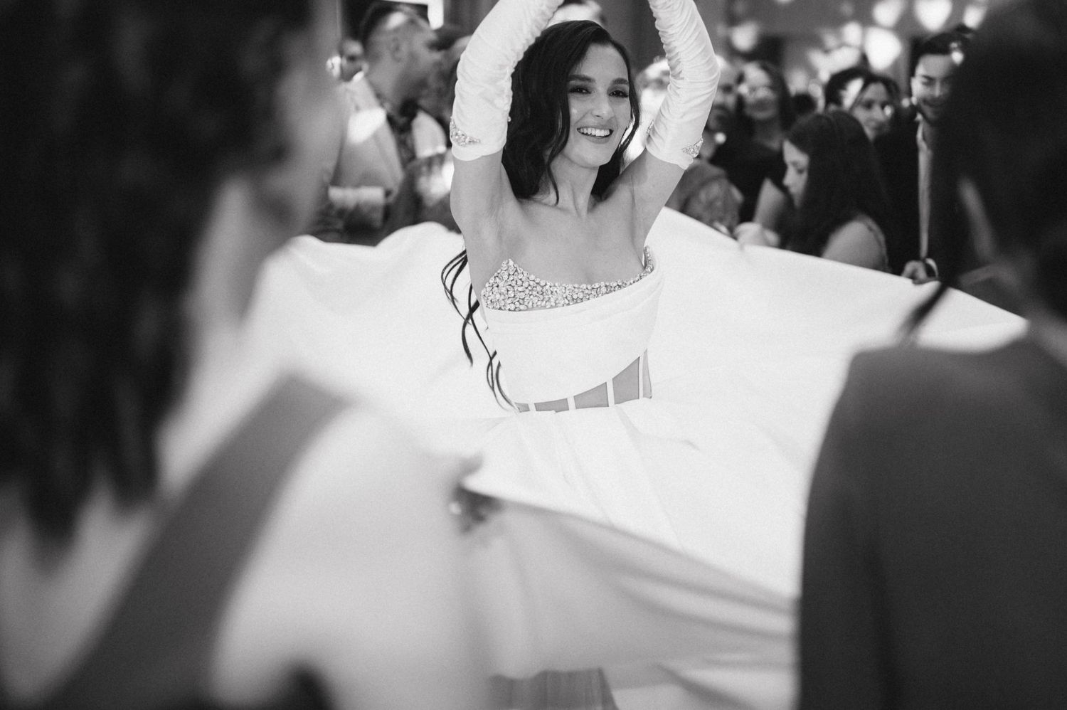 A bride dances joyfully in black and white during her wedding reception.