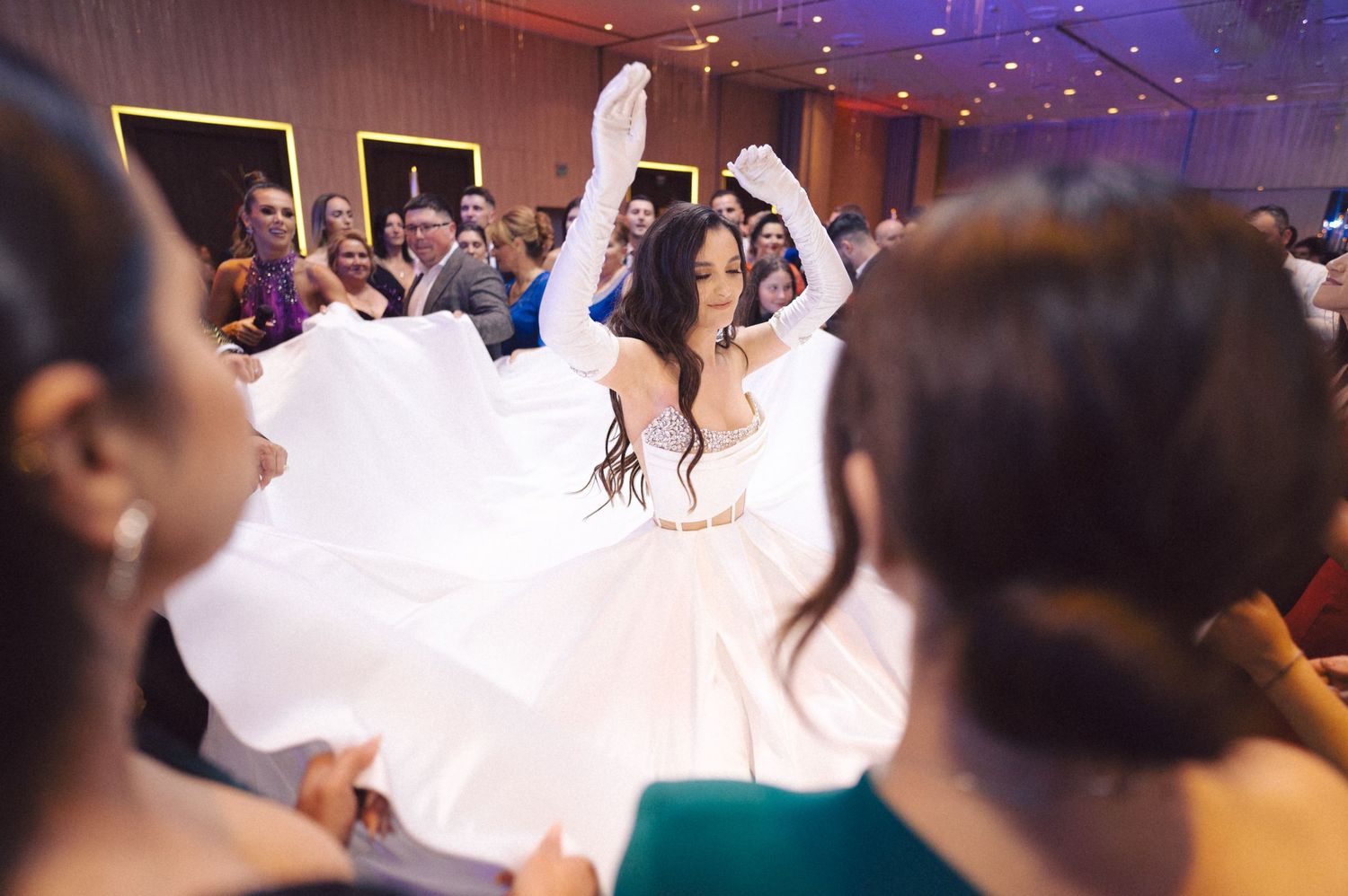 A bride twirls her wedding dress while dancing with guests at the reception.