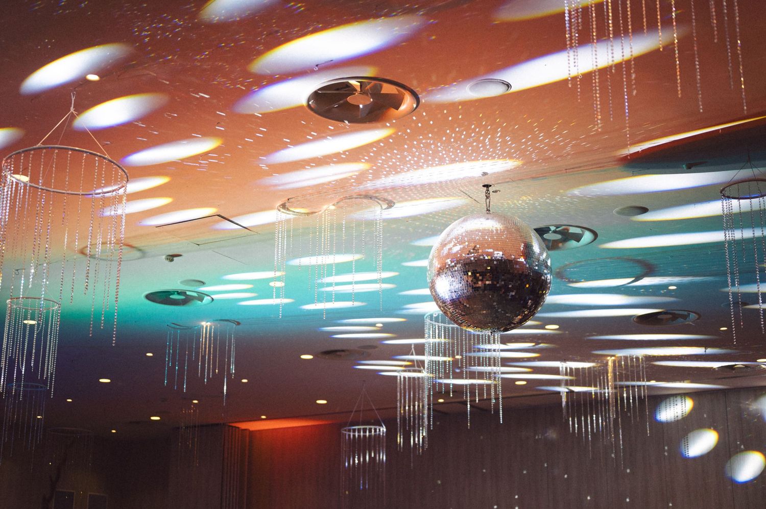 A sparkling disco ball hangs from the ceiling with blue lighting and scattered reflections.