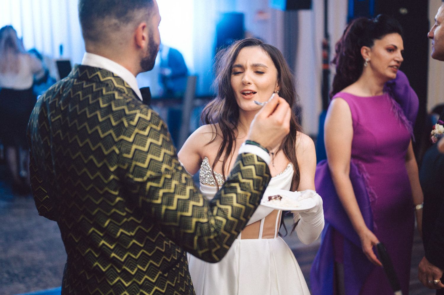 Wedding couple shares a playful cake-feeding moment during their reception celebration.