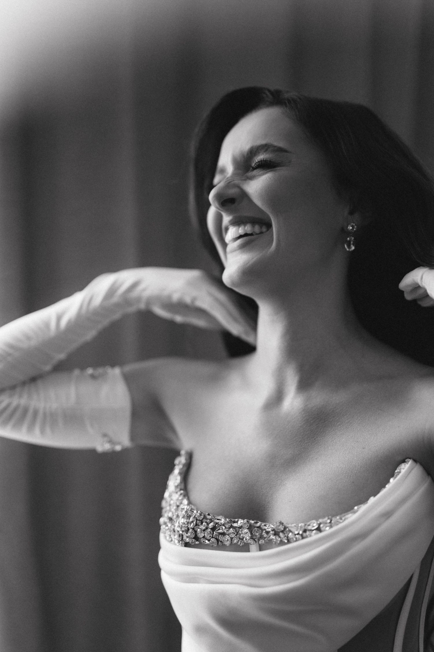 A joyful black and white bridal portrait captures a candid laughing moment in elegant attire.