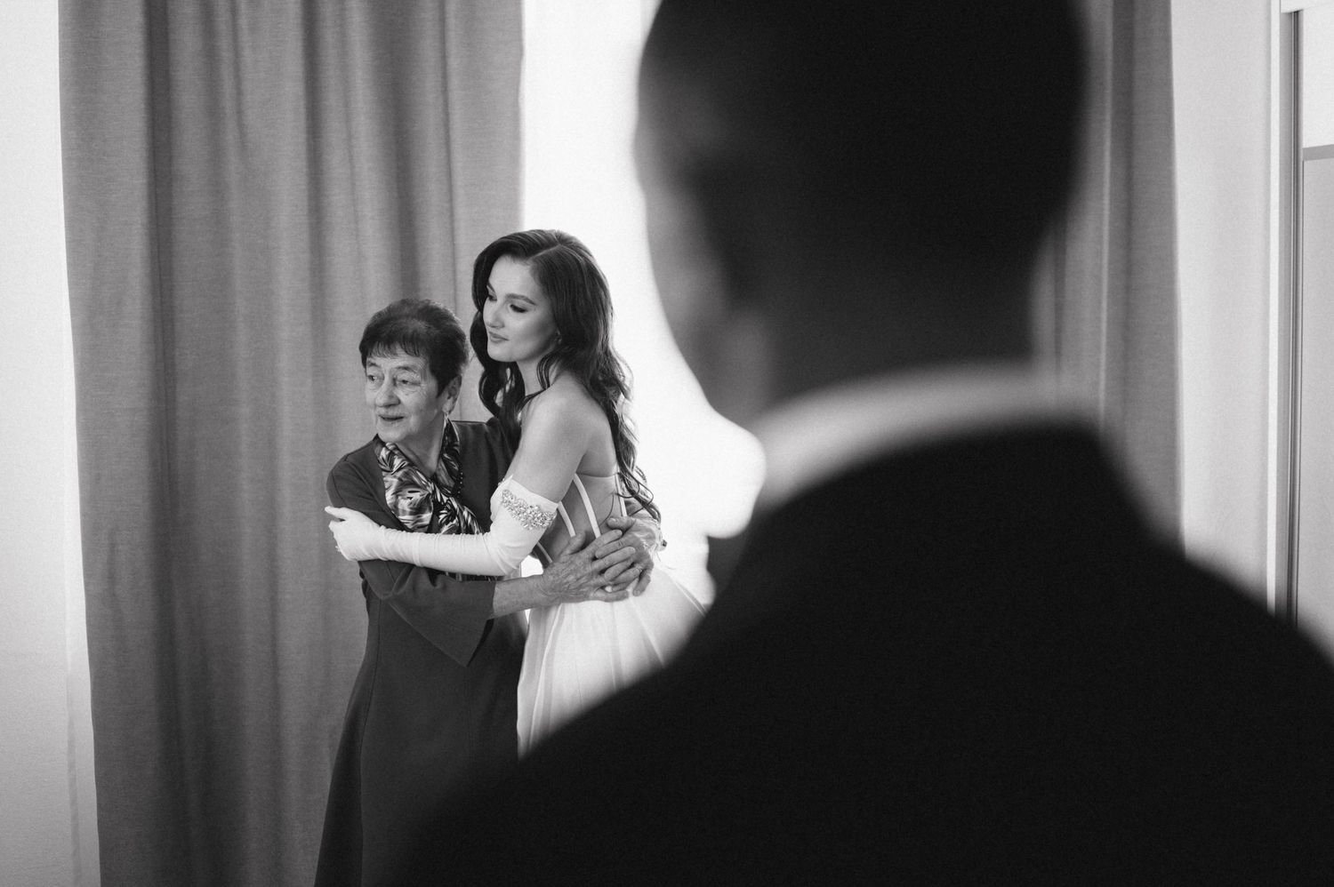 A candid black and white photo showing people looking at something together before a wedding ceremony.