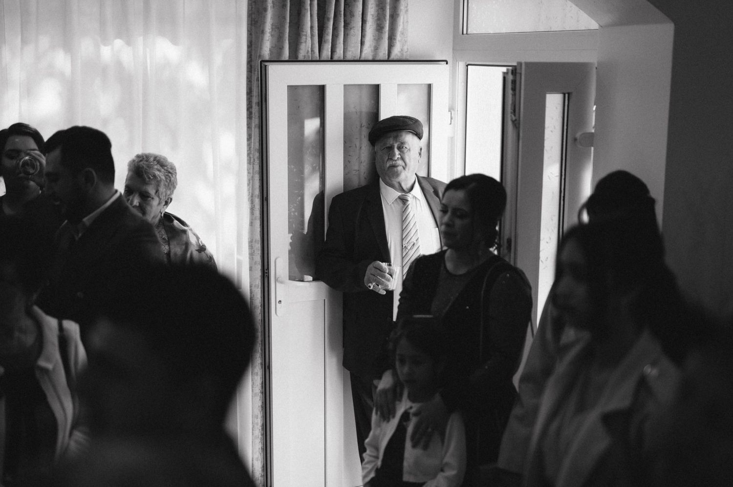 A black and white photo of guests mingling at an indoor event.