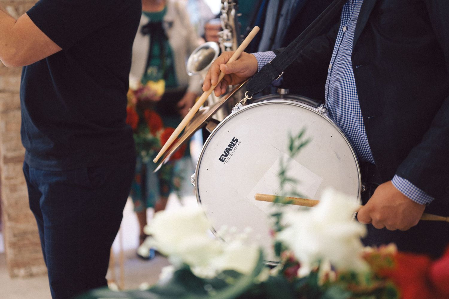 A close-up shot of a drummer playing a white drum with floral decorations nearby.