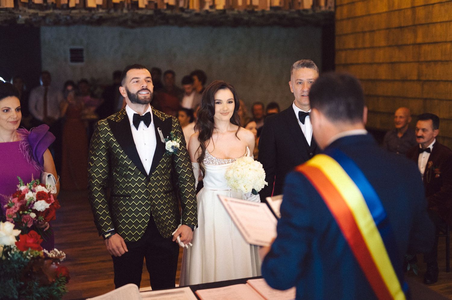 A wedding ceremony with decorative floral arrangements and brick wall backdrop.