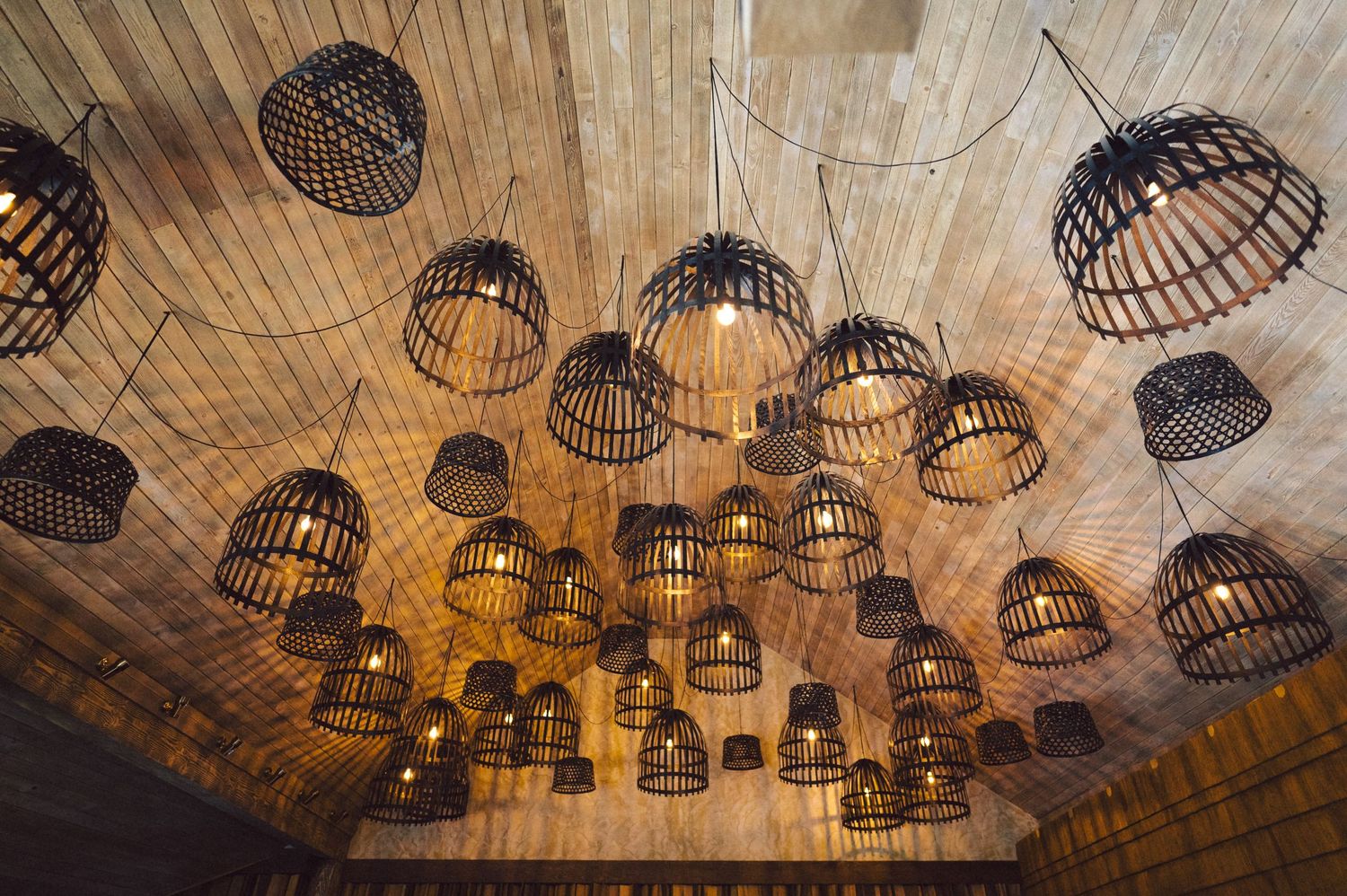 Rustic wooden ceiling decorated with multiple woven basket pendant lights creating ambient atmosphere.