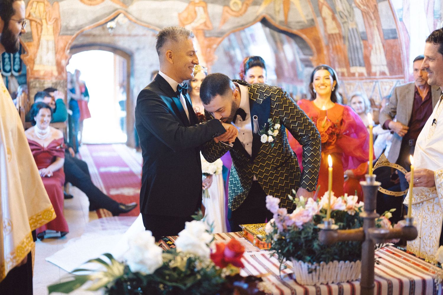 Traditional Orthodox wedding blessing ceremony with floral arrangements in a decorated church.