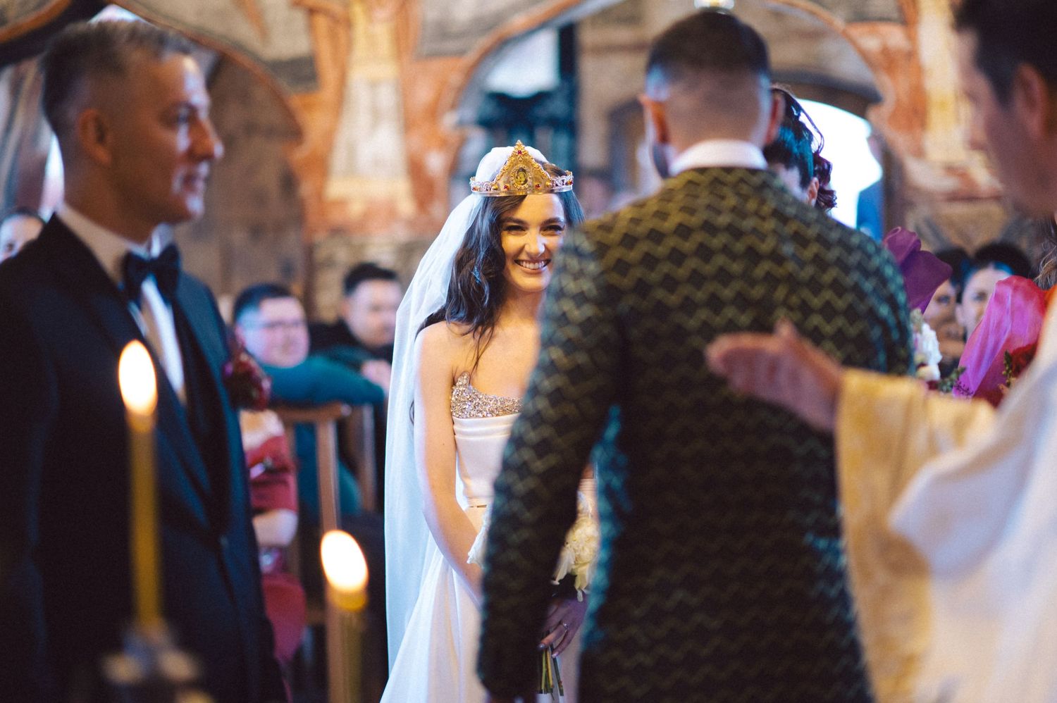 A couple exchanges vows during an intimate church ceremony with soft candlelight illuminating the ornate interior.
