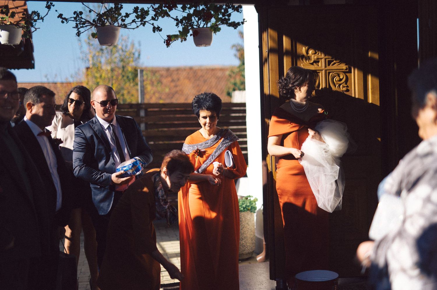 Wedding guests gather outdoors during an autumn celebration with trees in the background.