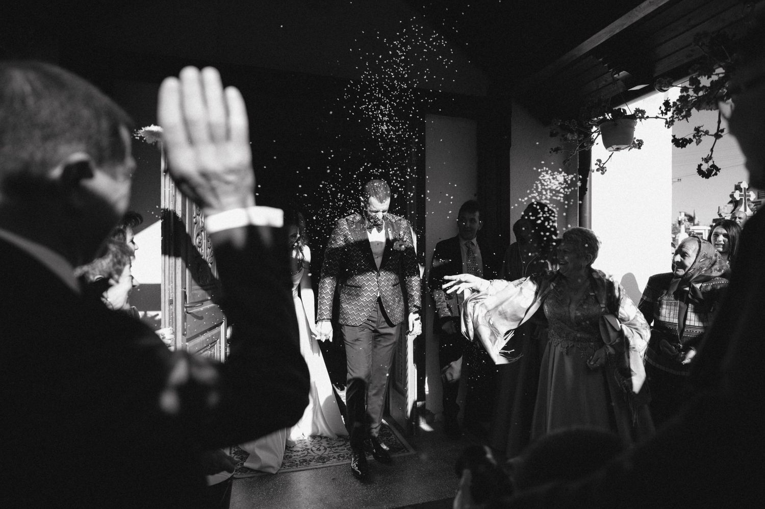 Black and white photo of a celebratory moment with raised hands and confetti at a wedding reception.