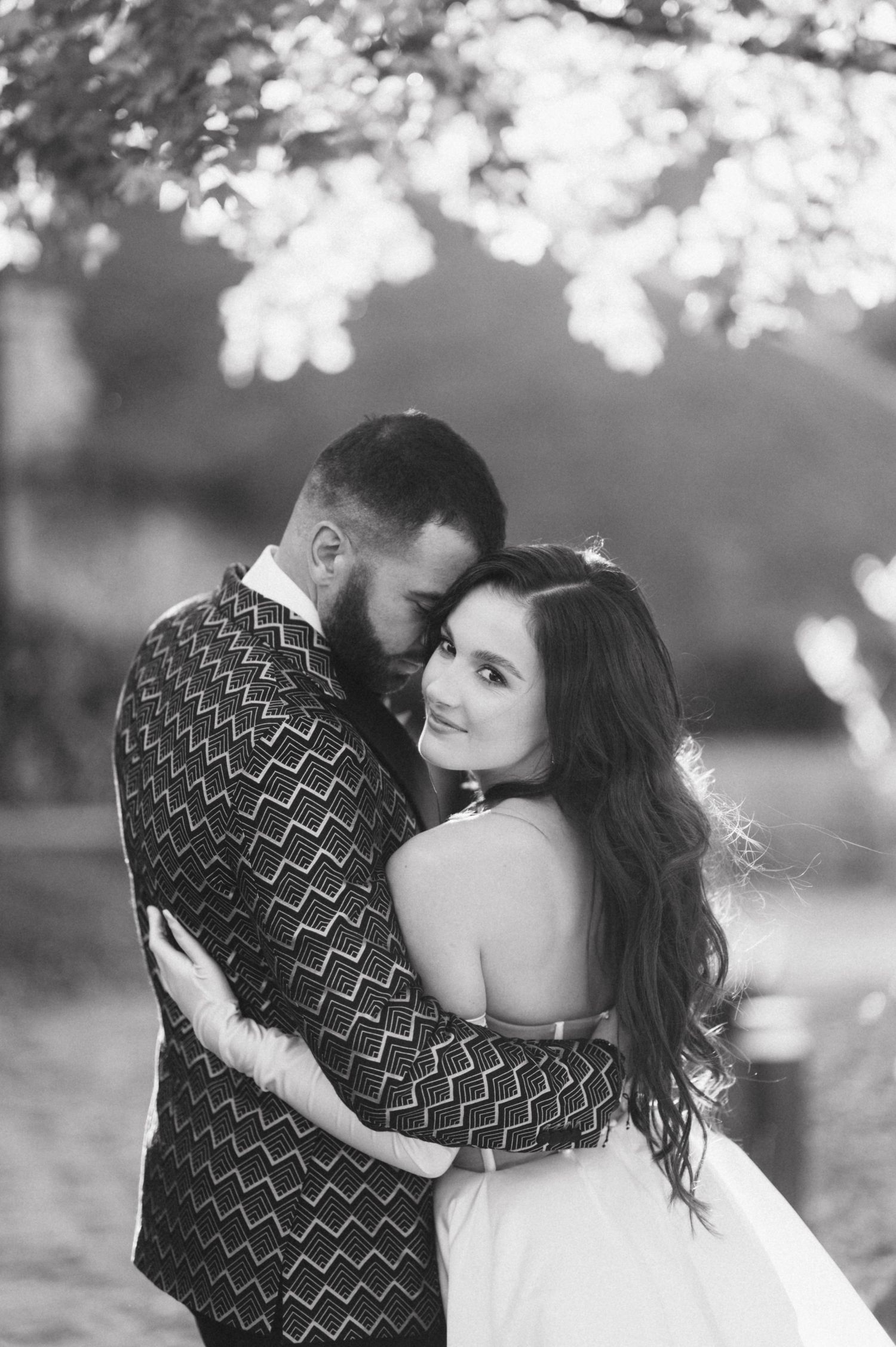 Intimate black and white portrait of a couple sharing a tender moment outdoors.