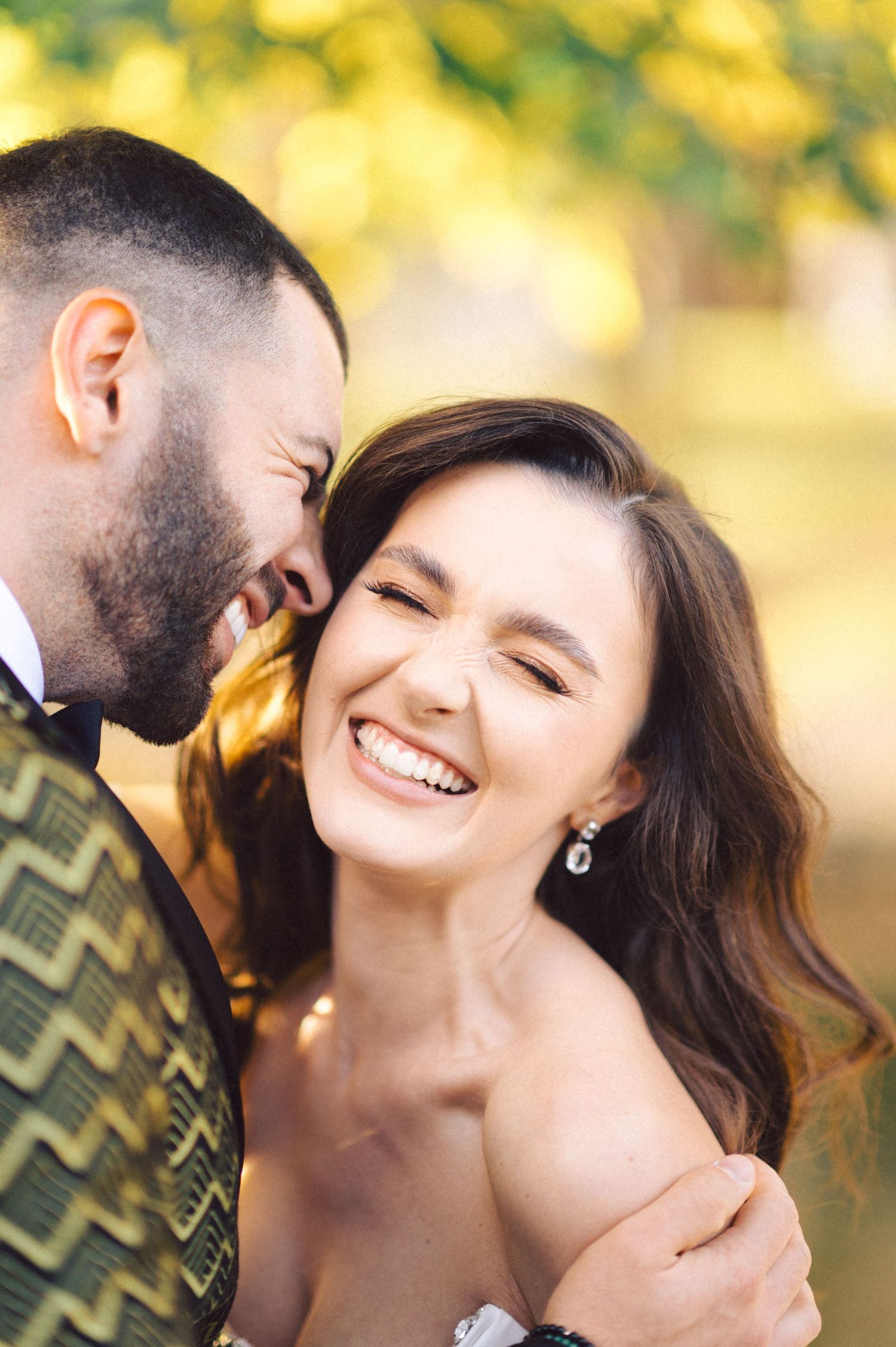 Joyful wedding portrait capturing a candid moment of laughter against warm autumn colors.