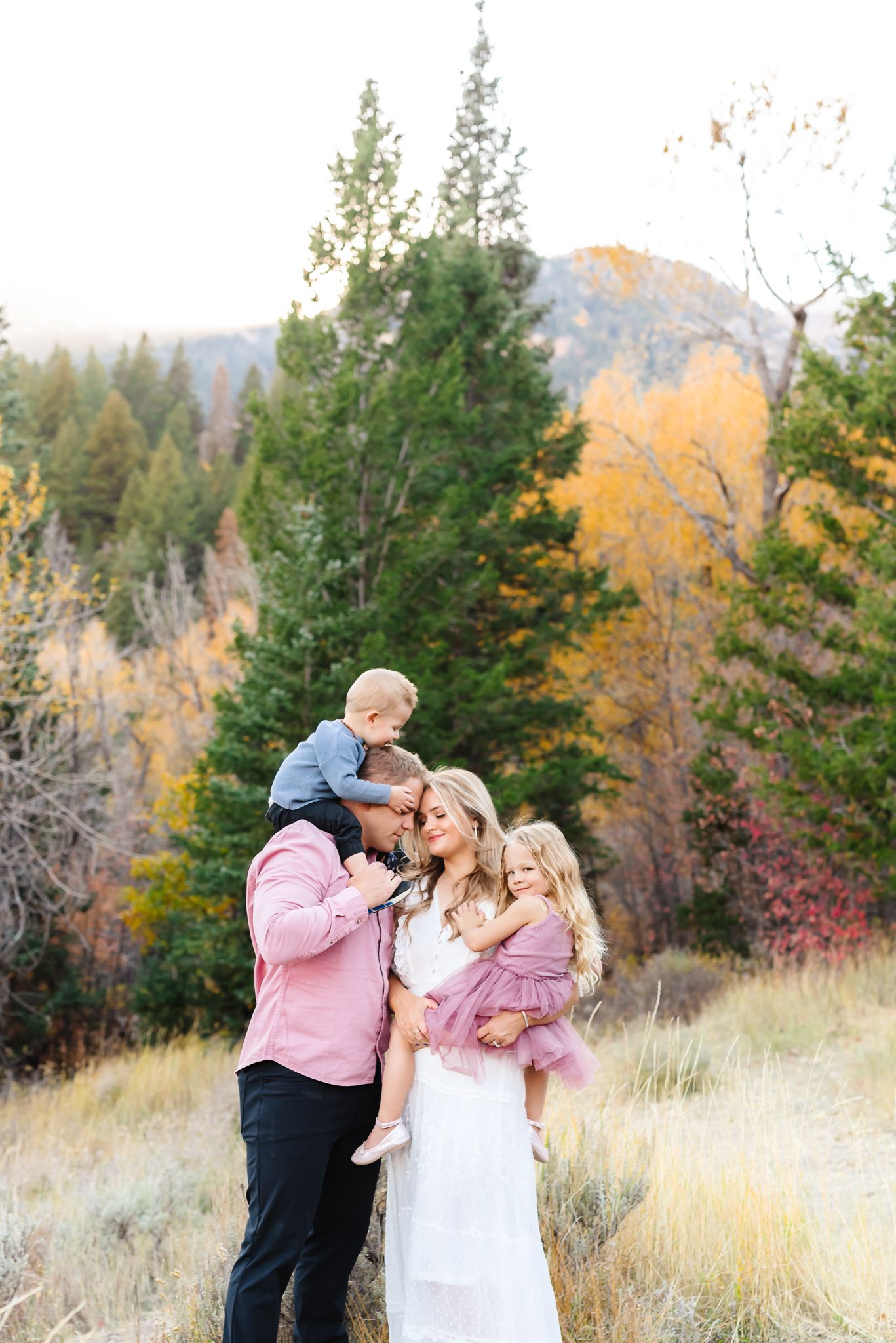 Family portraits in a mountain setting with autumn colors and evergreen trees.