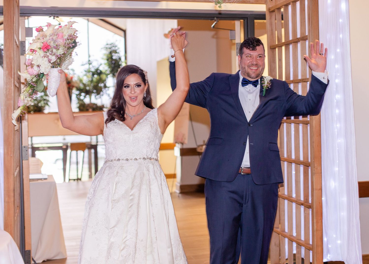 Wedding celebration in a venue with wooden beams and white drapery decorations.